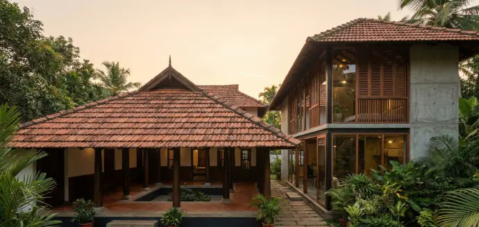 alt="Traditional Kerala-style home with sloped tiled roof and modern villa extension"
