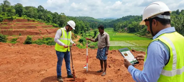 Engineers conducting soil testing and topography evaluation on a Kerala land plot before residential construction to check soil strength, slope, and suitability.